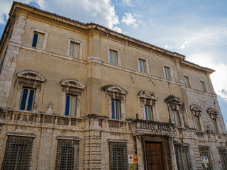 Fototapeta na wymiar Paisaje urbano con una fachada llena de ventanas y balcones en Spoleto en Italia, verano de 2019