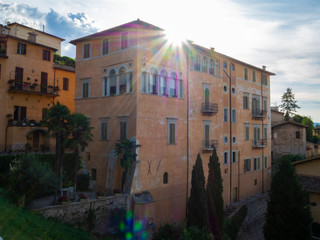 Fototapeta na wymiar Reflejos y flares, rayos de sol sobre un edificio en el casco antiguo de Spoleto, Italia, verano de 2019.