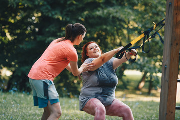 Obese woman together with her trainer during weight loss training, for the exercise of stretching...