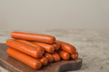 Raw sausages on a wooden board close-up and copy space. Boiled sausages for cooking.