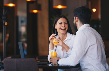 The couple is sitting at a table in a pub, drinking orange juice, talking