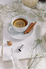 Obraz na płótnie Canvas Cup of tea with lemon, gypsophila, cashmere scarf, candle on white background. Lifestyle blog concept.