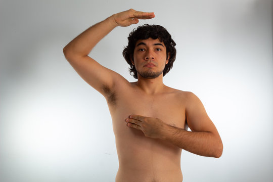 Young Naked Hispanic Man With Wavy Hair And Shaved Beard, Doing A Checkup On His Chest For Signs Of Breast Cancer