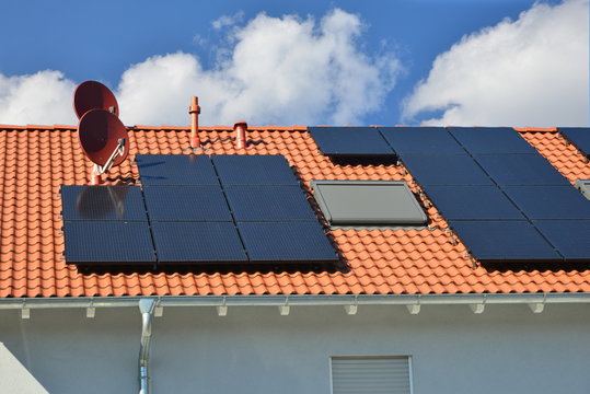 Solaranlage, Dachfenster, Dunstabzüge und Satelliten-Antenne auf einem Ziegeldach montiert