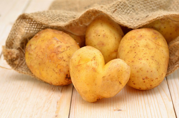 young potatoes poured out of the sack and heart-shaped potatoes