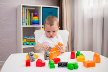 a small boy plays a multi-colored construction set at a table in the children's room