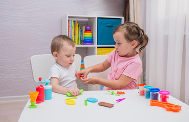Fototapeta premium a little boy and girl play play-doh at a table in the children's room
