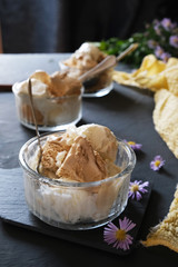 Ice cream in three glass bowls on a dark table.
