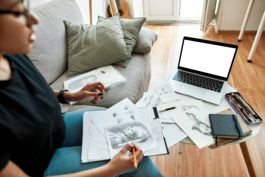 New skill. Young afro american girl watching pencil drawing course online on laptop while sitting on sofa at home. Distance education