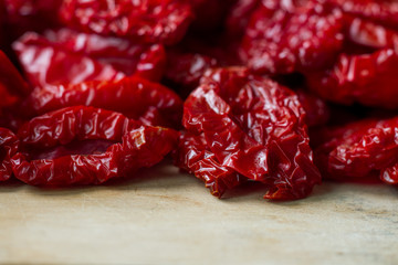 Close-up sun-dried tomatoes with spices and olive oil on wooden cutting board, background or concept, selective focus