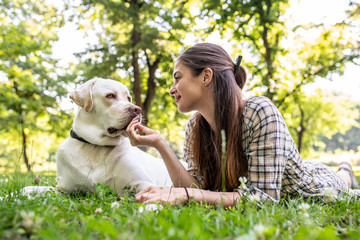 A young woman lying on a meadow with her beautiful dog on a sunny day