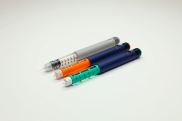 three insulin pens, injector pen on a white background, for hormone therapy for patients with diabetes. selective focus