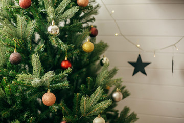 Modern gold and red baubles on Christmas tree. Hanging shiny glitter ornaments on christmas tree,...
