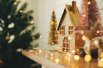 Merry Christmas. Stylish christmas wooden house, glitter christmas tree and golden reindeer in...