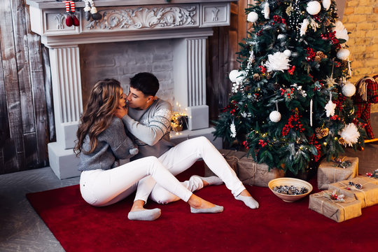 Nice couple in love sitting on carpet in front of fireplace. bea