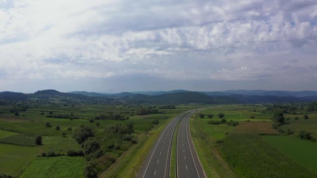 Aerial shot of motorway on a cloudy day and a hippie van entering the shot.