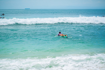 Sexy slim girl riding on surf board in the ocean. Healthy active lifestyle in summer vocation.