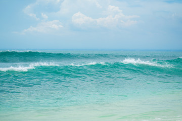 An ideal tropical sandy beach for surfing on the ocean. Beautiful clear turquoise water and waves.