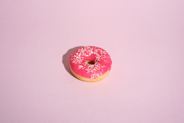 Pink donut with sprinkles, sweet glazed dessert food on pink minimal background, angle view copy...