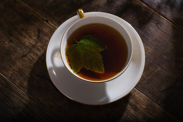 Vintage cup of tea with gold decoration on the old wooden table on which berries lie