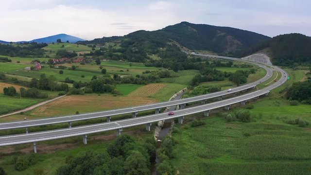 Aerial shot of hipster van driving on a long motorway viaduct.