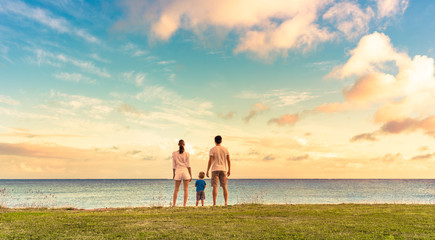 Fototapeta premium Family of three watching the sunset together holding hands. 