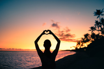 silhouette of a person on the beach making heart symbol with hands