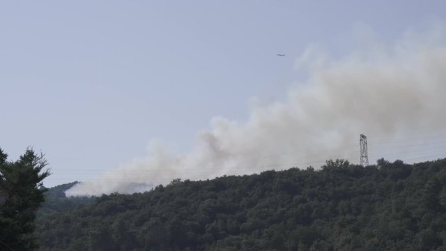 Firefighting airplane fly over a forest fire on a sunny day
