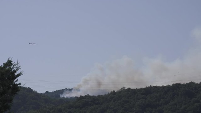 Bombardier Q400 flying over a bush fire on a sunny day, summer drought