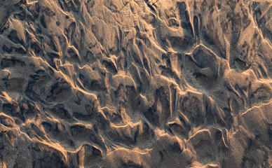 rippled wet sand background texture on beach at sunset