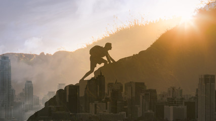 Young determined man climbing up mountain overlooking the city. People, power, challenging...