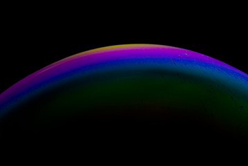 Detail of light in a soap bubble, allusion to the micro universe in a studio with a black background, use of natural and artificial light.