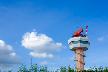 Secondary surveillance radar tower for tracking position of the aircraft behind the trees, sunny day with Blue sky background