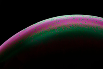 Detail of light in a soap bubble, allusion to the micro universe in a studio with a black background, use of natural and artificial light.