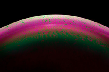 Detail of light in a soap bubble, allusion to the micro universe in a studio with a black...