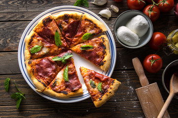  Freshly baked pizza with salami slice served on wooden table