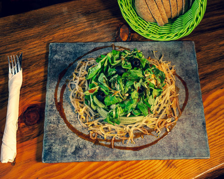 Closeup shot of a Verdina salad in a slate plate on wooden table