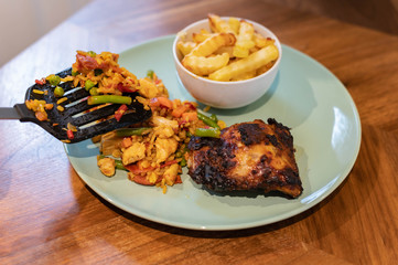 isolated Chicken chorizo with chips and chicken breast on wooden kitchen table being dished out