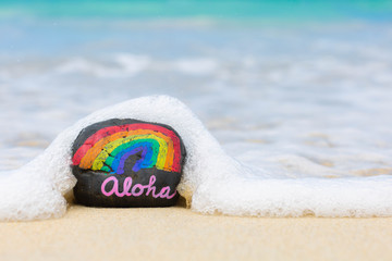 Aloha word on hawaii beach sand. Hawaiian rainbow.