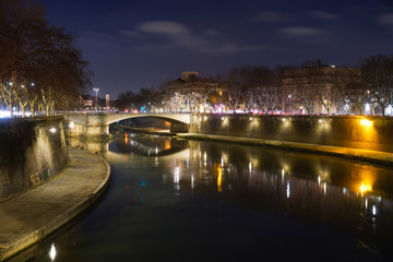 Fototapeta na wymiar Foto noturna de longa exposição da ponte iluminada sobre o rio na cidade de Roma.