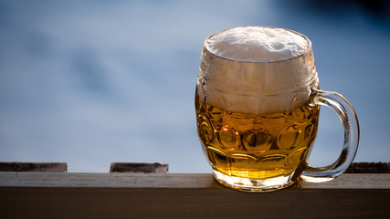 A pint of foamy lager beer stands on a lodges balcony edge situated in a winter landscape.