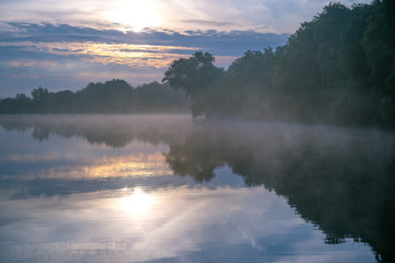 Fototapeta na wymiar Berenbosteler See an einem nebligen Morgen zum Sonnenaufgang im Sommer