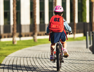 Rear view of a schoolgirl riding a bicycle to school.