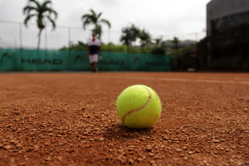 Close up of tennis ball on clay court. Tennis ball on a clay court. Red clay tennis court. Sand on a tennis court