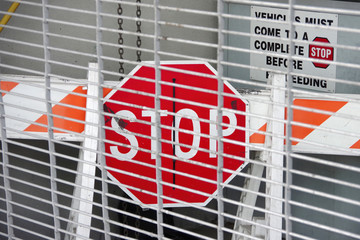 A barrier with a STOP sign behind a metal entry gate of a large city garage