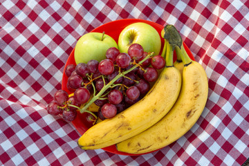 Plate with fruits on a camping-type tablecloth, reusable crockery and cutlery