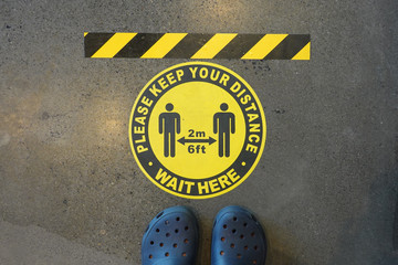 Yellow sticker on the ground informs people to keep social distancing of 6 feet (2 meters) during the Covid-19 pandemic.