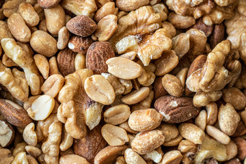 Mix of seeds, walnut, peanuts and almonds in a bowl on wooden table.