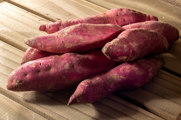 Red sweet potato pile on wooden background in Brazil