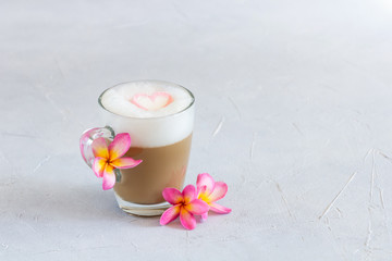Cup of cappuccino with marshmallow heart on top decorated with flowers. Copy space.